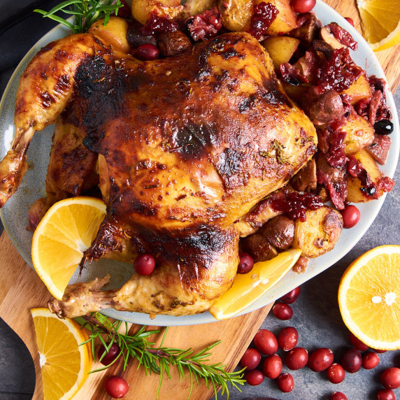 A plate of Cranberry Rosemary Roasted Chicken, surrounded by roasted potatoes and mushrooms