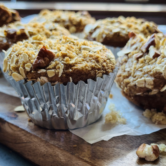 Muffin with streusel topping on a wood cutting board. 