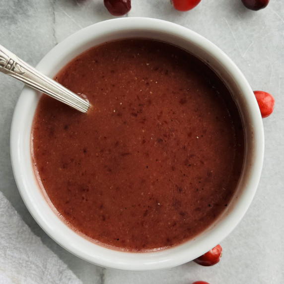 Cranberry vinaigrette salad dressing in a white bowl on a marble board.