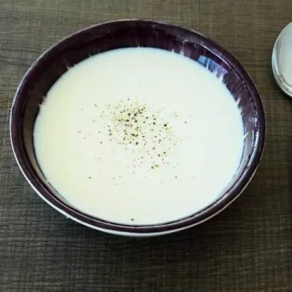 Cream of Corn Soup served in a bowl with a spoon on the side