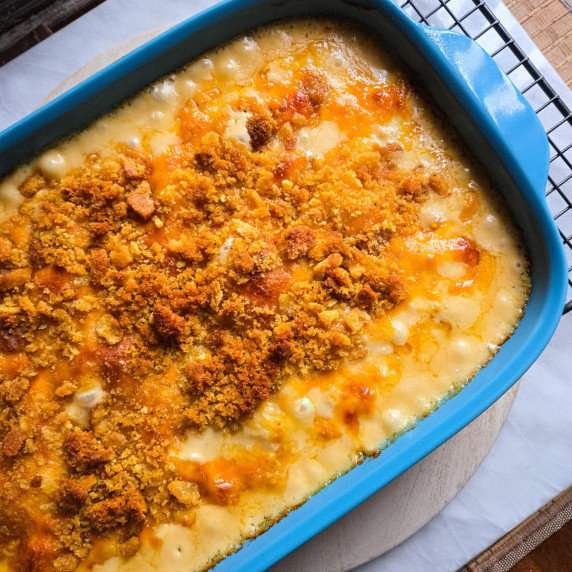 Blue baking dish full of creamy casserole with golden crumbs on top.