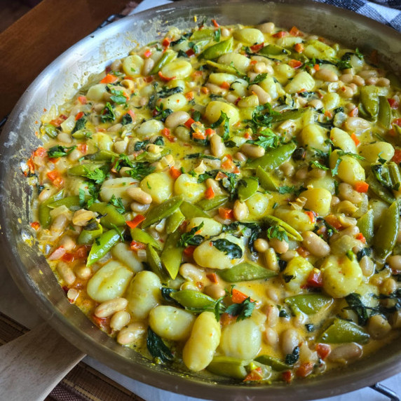 A skillet full of plump gnocchi, green veggies, and pesto sauce.