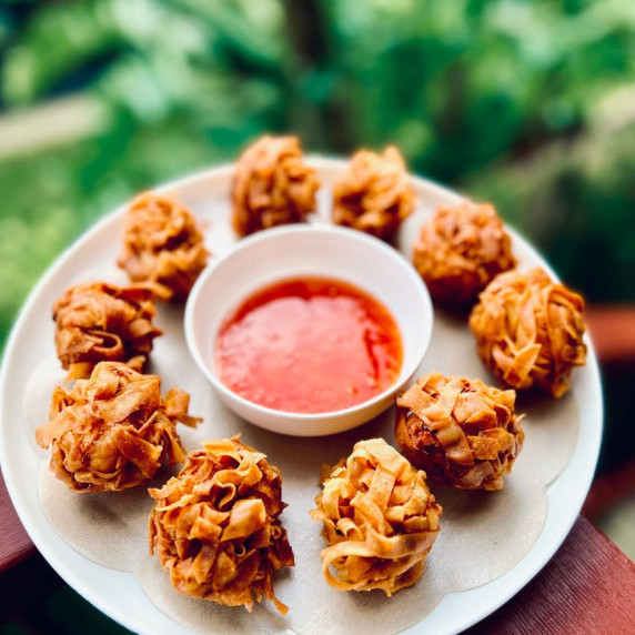 fried prawn balls on white plate with sweet chilli sauce in a bowl. Garden background