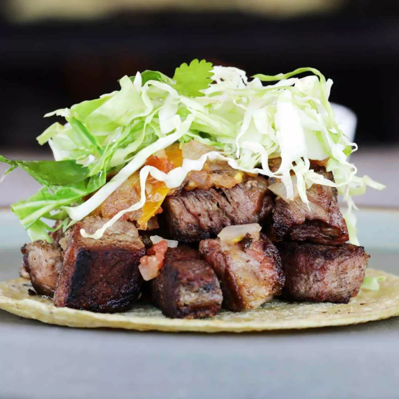 Crispy Ribeye Steak Tacos with Grilled Tomato Salsa and piled high on a corn tortilla.