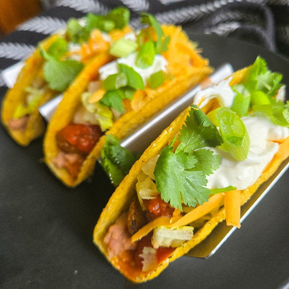 Golden taco shells stuffed with taters, orange cheddar, greens, and white sour cream
