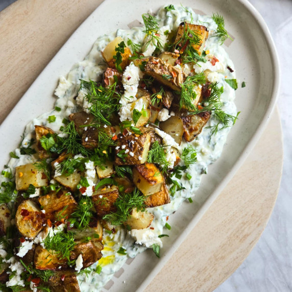 Crispy, golden taters on a bed of creamy tzatziki with pops of green herbs and red pepper flakes