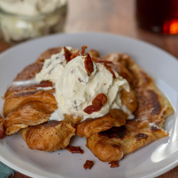 Croissant French Toast with Maple Bacon Whiped Cream on a white plate