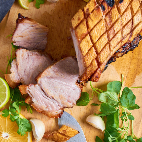 Cuban Air Fryer Pork Shoulder with crispy crackling on a wooden board, surrounded by herbs.