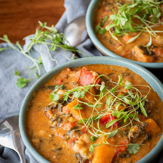 Two bowls of soup sprinkled with microgreens