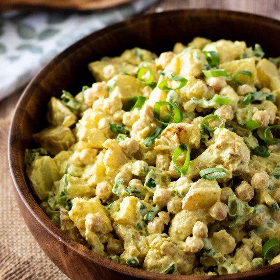 A wooden bowl full of Curry Cauliflower Potato Salad