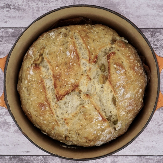 Freshly baked no knead olive bread in a cast iron pot