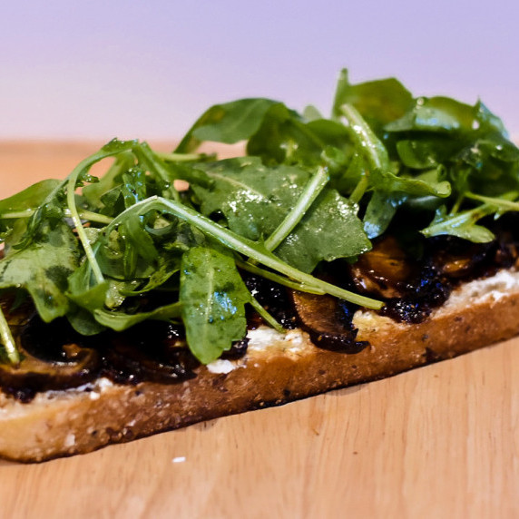 Bread topped with goat cheese, fig jam, mushrooms, and arugula.