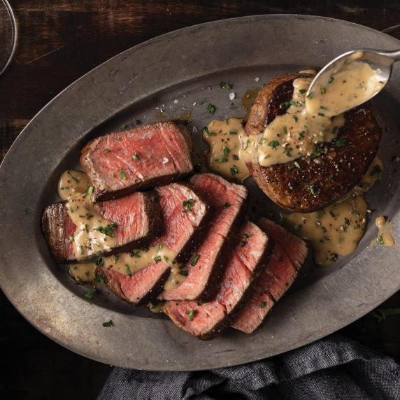 Elk Steak Diane on a plate, perfectly seared and topped with a creamy brandy and mustard sauce.