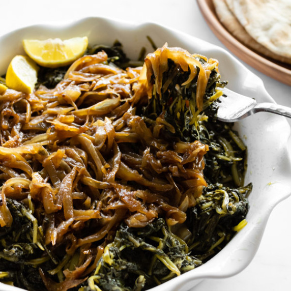 dandelion greens with caramelized onions scooped up with a fork.