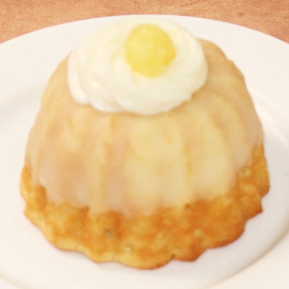 Small lemon bundt cake, glazed and topped with cream cheese icing and lemon curd