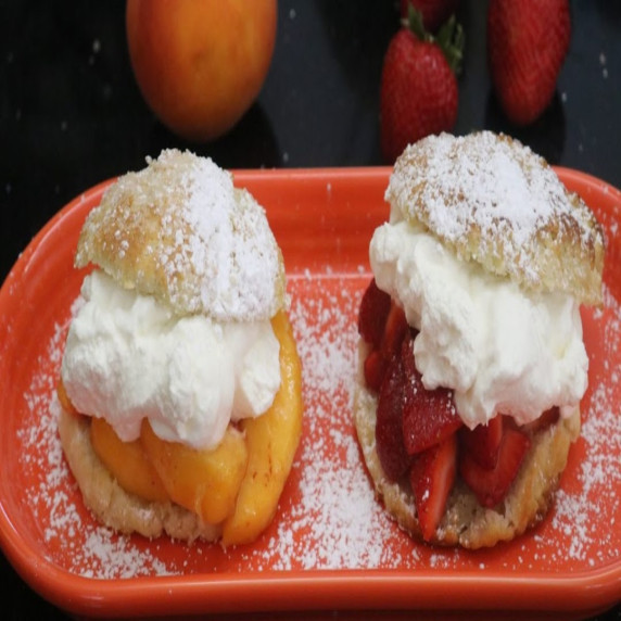 Two dessert shortcake biscuits: one with peach, the other with strawberries.