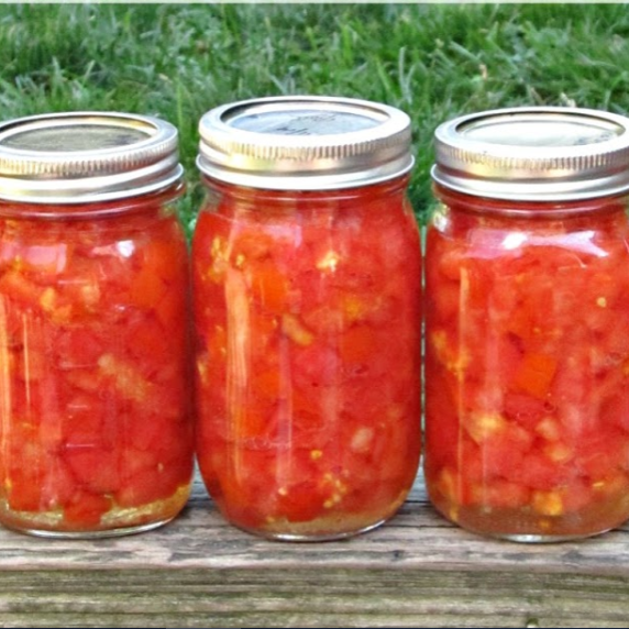 jars of home canned diced tomatoes lined up on a ledge