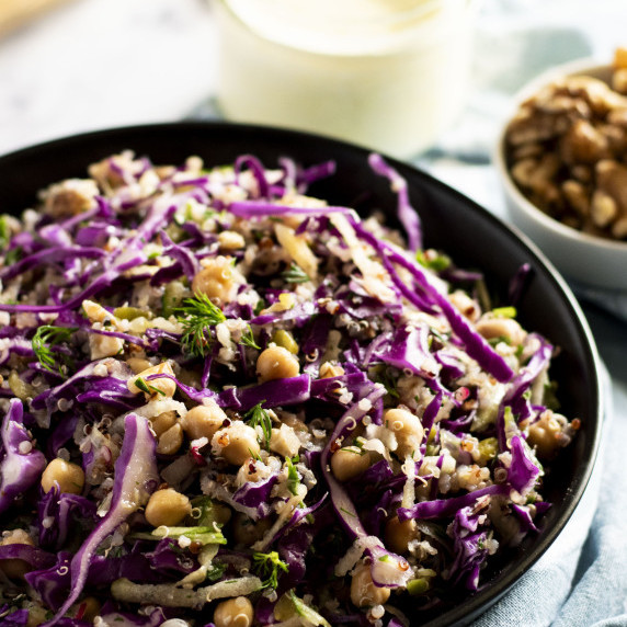 A bowl of dill, apple and red cabbage slaw with greek yoghurt dressing in the background.