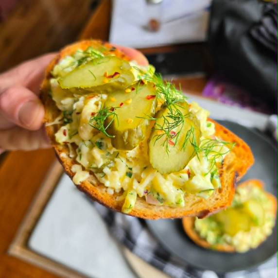 Golden toast topped with cheesy egg salad and green pickles & dill