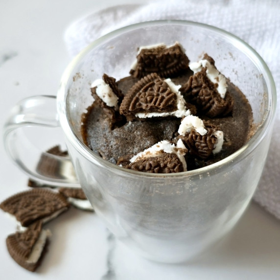 Oreo Mug Cake Recipe with a few crushed Oreos on the side.