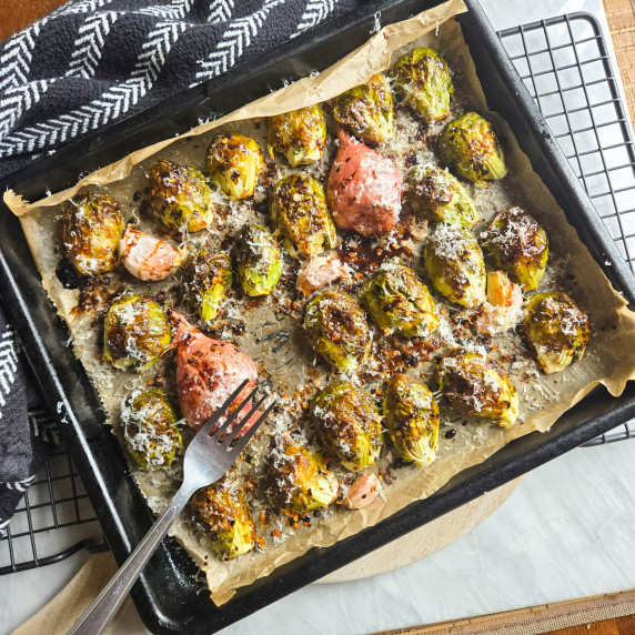 A tray of roasted brussel sprouts against a black patterned towel.
