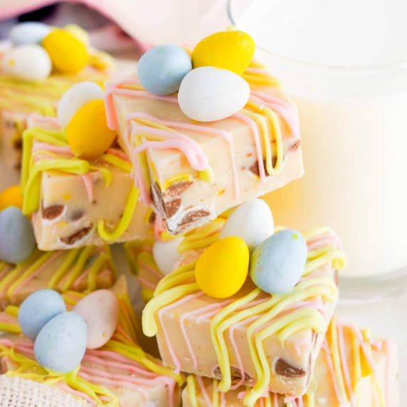 A stack of white chocolate Easter Fudge from the side decorated with chocolate mini eggs.