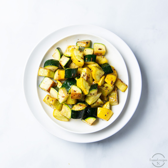 sautéed zucchini and yellow squash in a white bowl on a white countertop