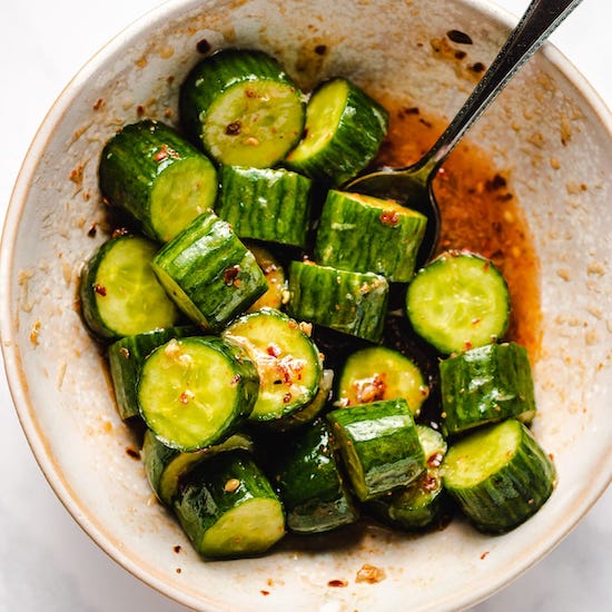 Cucumbers with honey chili vinaigrette sauce in a stoneware bowl with a spoon
