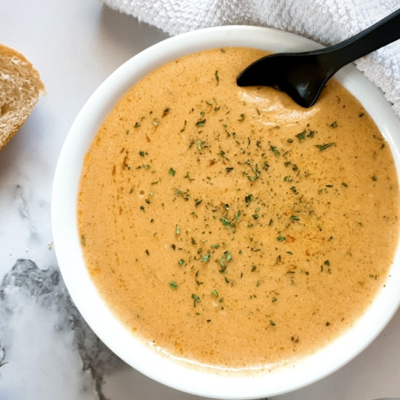 Cajun Alfredo Sauce recipe in a white bowl with a small black spoon.