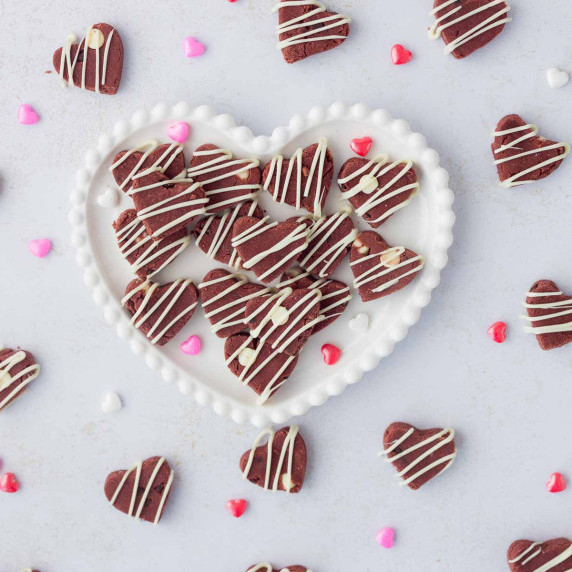 Edible Red Velvet Protein Cookie Dough Hearts on white decorative heart plate with hearts around 