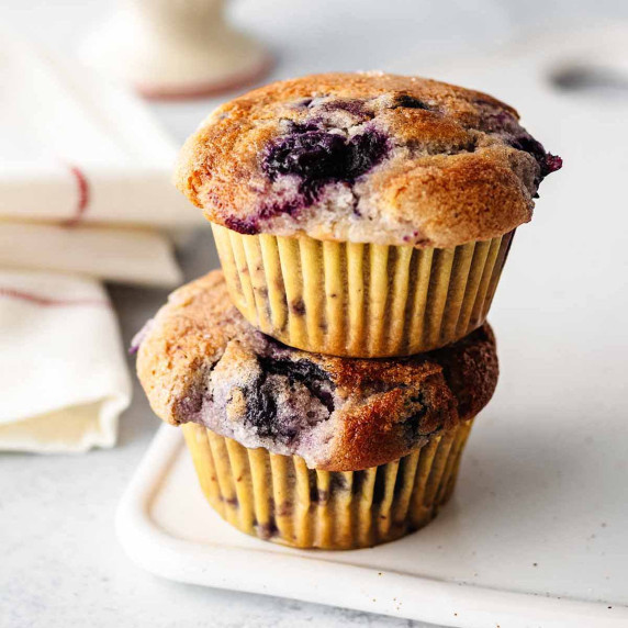 Two eggless blueberry muffins in a stack on a white platter.