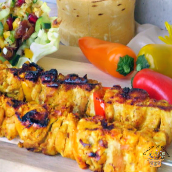 Egyptian chicken kebabs on skewers with a bell peppers and onions on a plate