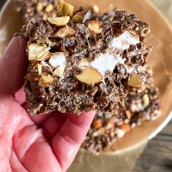 Cut shot of a Rocky Road Rice Krispie Bar, showing chocolate, marshmallows, and almonds.