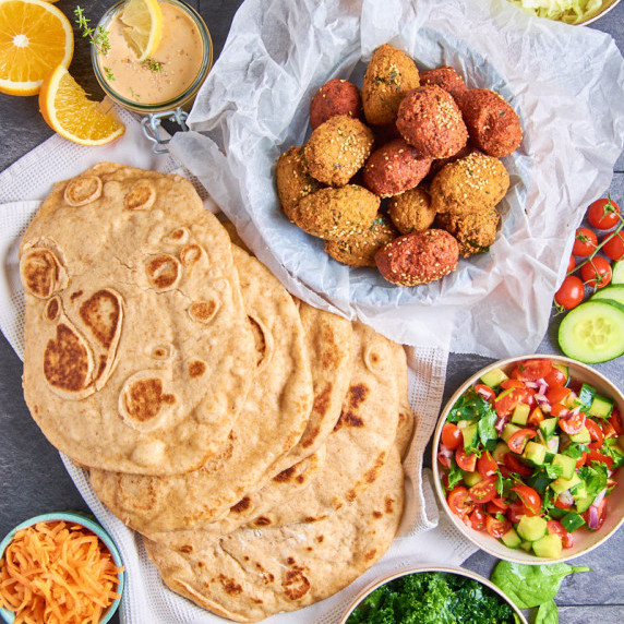 A feast of Vegan Falafel Wraps, Naan bread, mixed salad, Tahini dressing and pickled cabbage.