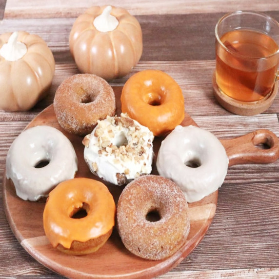 Arrangement of pumpkin donuts with cinnamon sugar, maple glaze, and cream cheese icing with walnuts.