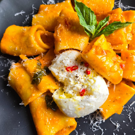 Paccheri noodles coated in a lush orange sauce with creamy white burrata and fiery red chilis