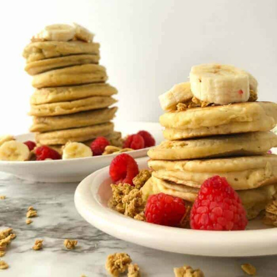 Two tall stacks of fluffy almond milk pancakes with fruit.