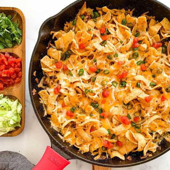 A pan of walking taco casserole with a wooden side dish 