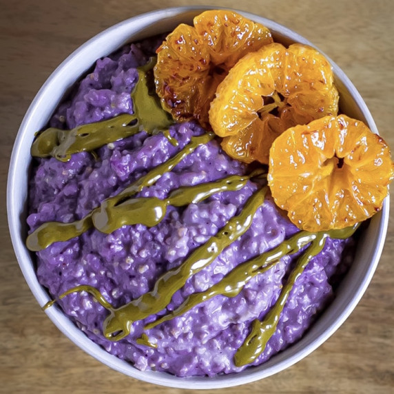 Vegan millet porridge with blueberry powder, caramelized clementines, and pistachio butter