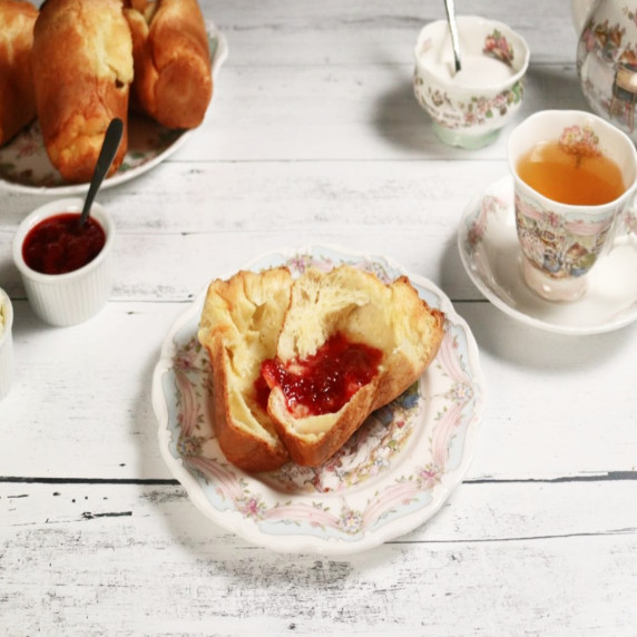Split popover with jam surrounded by tea and extra popovers