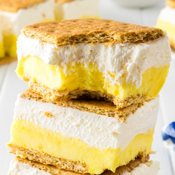 Image of 2 layered frozen lemon s'mores ice cream sandwiches stacked with the top one missing a bite