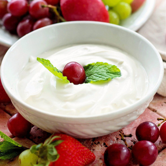 Fruit dip in a white bowl topped with mint and a grape
