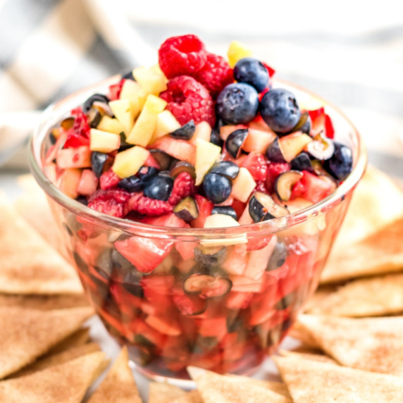 Clear bowl of chopped fruit salad surrounded by homemade cinnamon tortilla chips