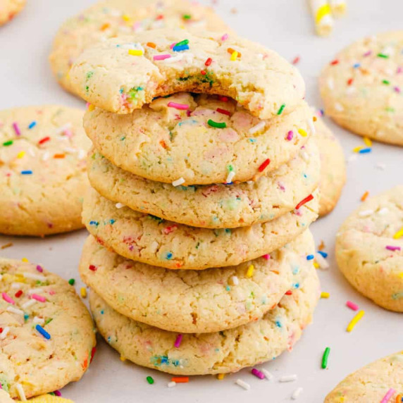 Square view of a stack of funfetti sprinkle cookies with the top cookie missing a bite.