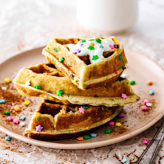 Stack of funfetti waffles on a pink plate.
