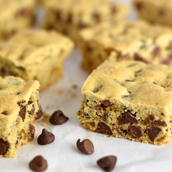 Gluten Free Chocolate Chip Cookie Bars and a few chocolate chips scattered on parchment paper.