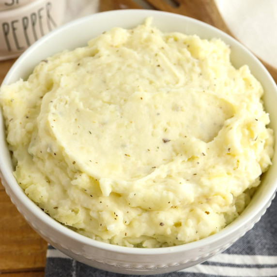 A close up view of a bowl of herb garlic cream mashed potatoes.