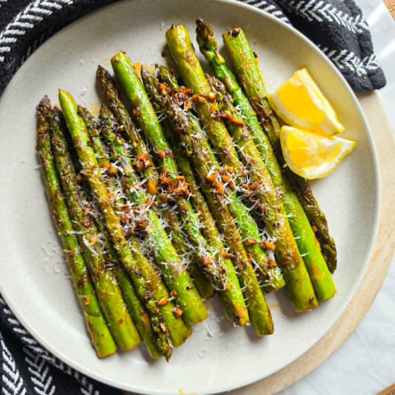 Green asparagus on a white plate against a black towel.