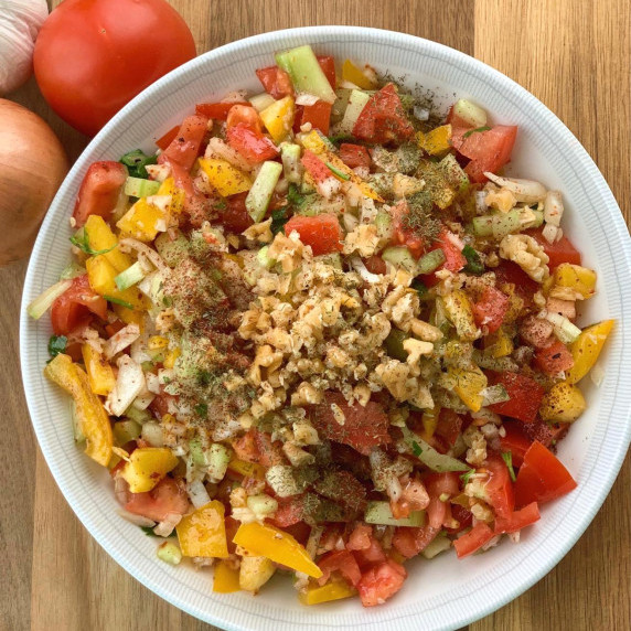 A large bowl of gavurdag salad, prepared with chopped peppers, tomatoes, walnuts. 