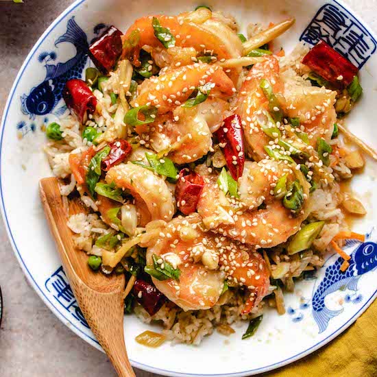 Shrimp, garlic, ginger, spring onions, red pepper, sesame seeds in a white and blue plate